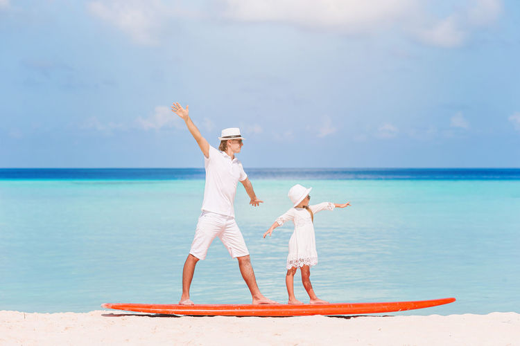 Full length of father and daughter standing on paddleboard