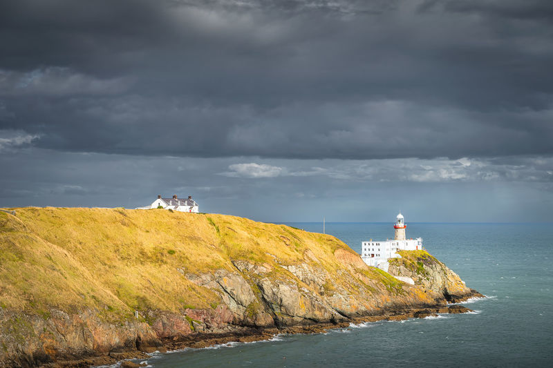 Dark storm clouds and baily lighthouse in howth peninsula, dublin