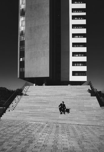 Man sitting on staircase against building