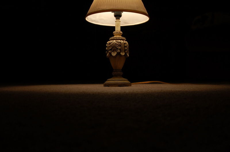 Close-up of illuminated lamp on table against black background