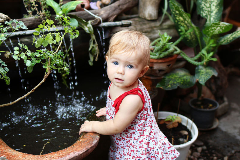 Portrait of cute baby girl standing by pond