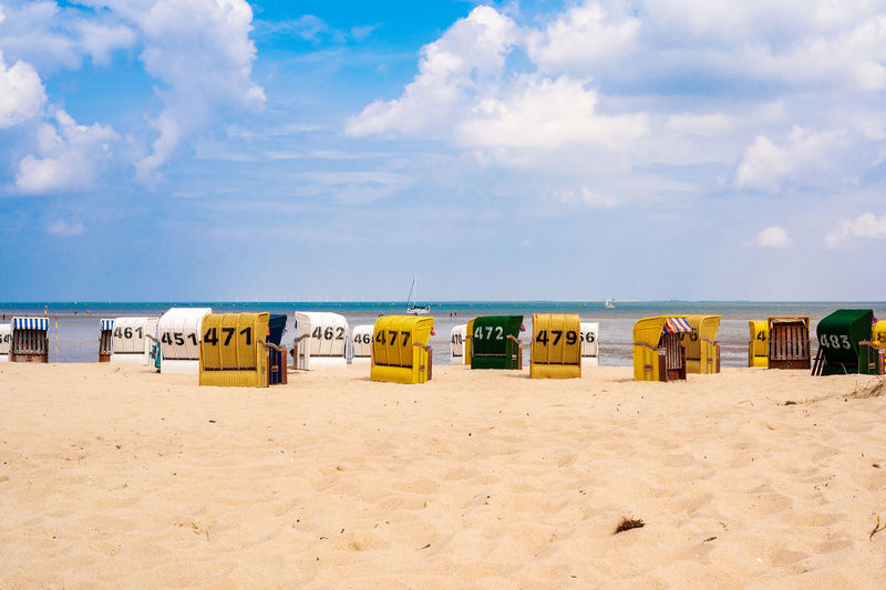 Hooded chairs on beach against sky