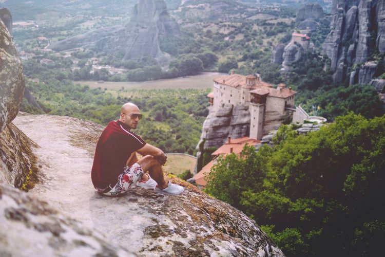 Side view of bald man sitting on rock formation