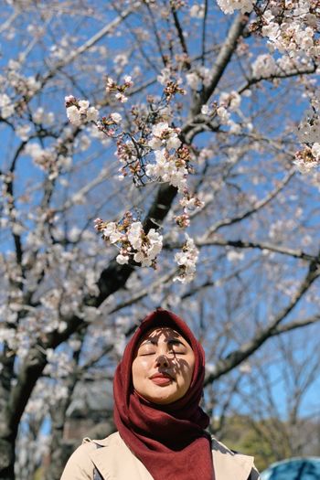 Low angle view of a girl and cherry blossoms on tree 