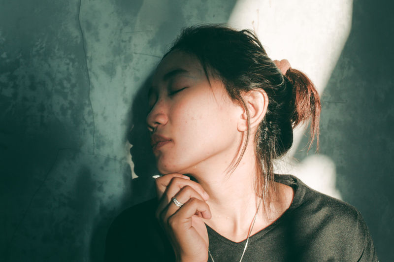 Close-up of young woman leaning on wall