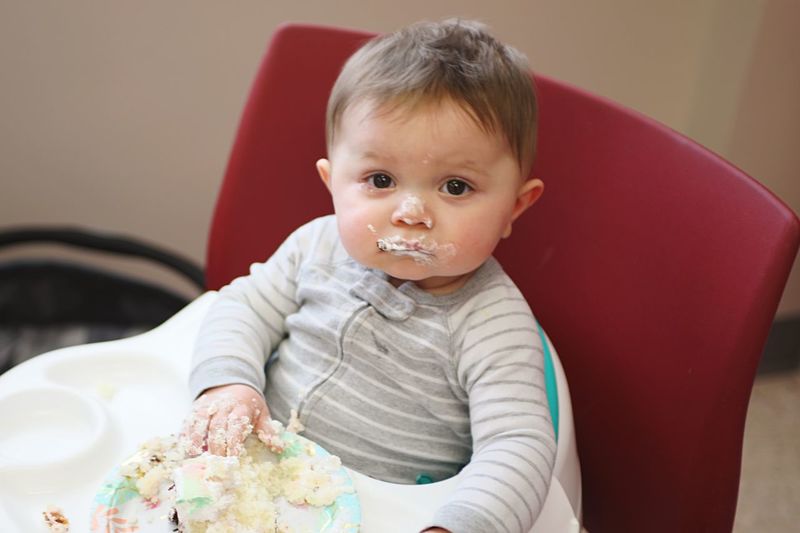 Portrait of cute baby boy with messy face sitting on high chair