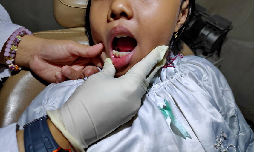 Close-up of dentist examining girl teeth