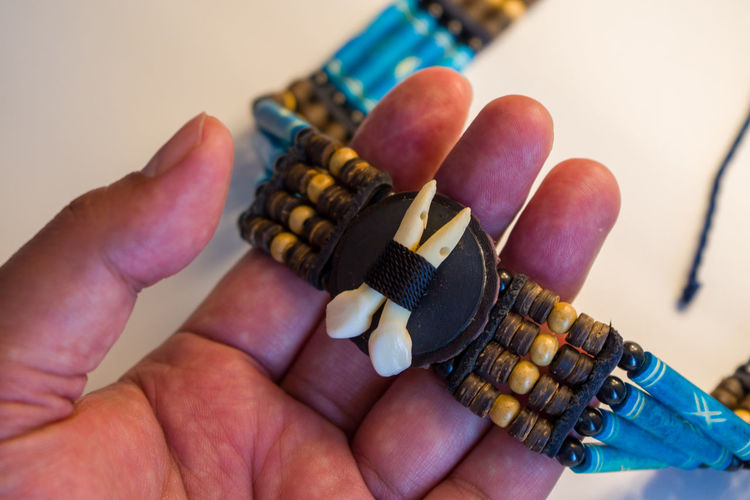 Close-up of hand holding tribe necklace.