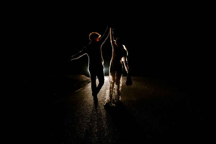 Rear view of people walking on street at night