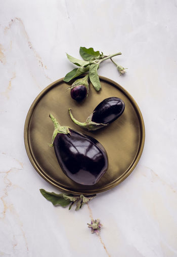 Beautiful minimalistic composition of eggplants on dish , marble background.