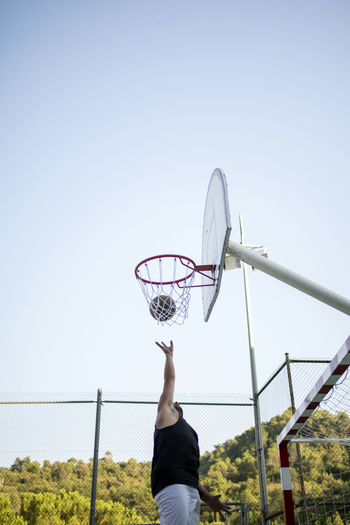 Low angle view of man playing basketball against clear sky