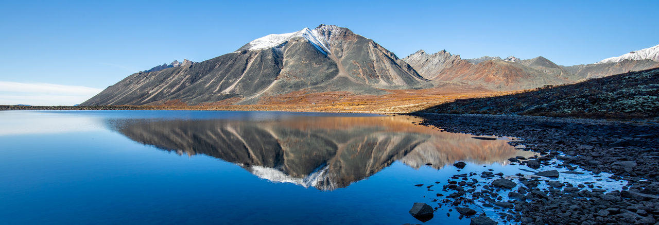 Scenic view of lake and mountains against blue sky
