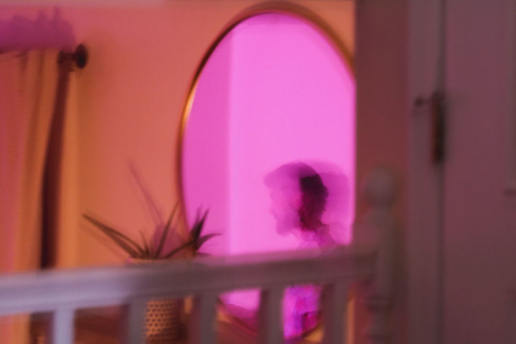 Silhouette of woman against pink wall at home