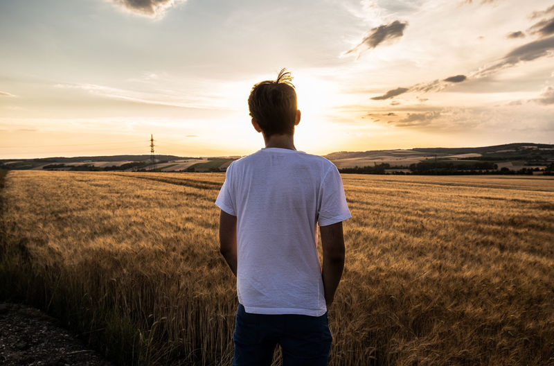 Rear view of man standing on field against sky