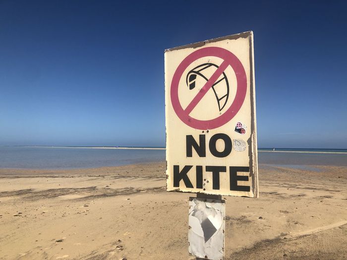 Information sign on beach against clear sky