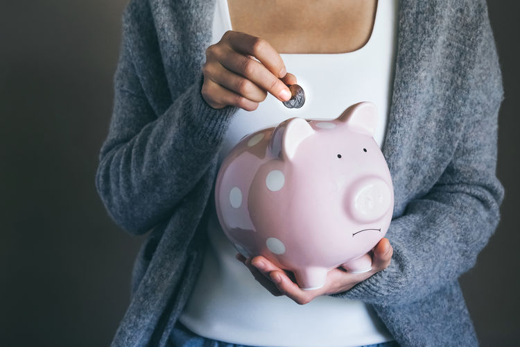 Woman putting coins in sad piggy bank. saving money for household payments. economic crisis concept
