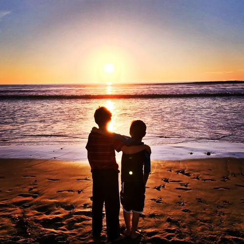 Friends standing on beach during sunset