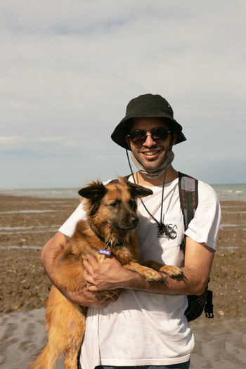 Man with dog on shore against sea