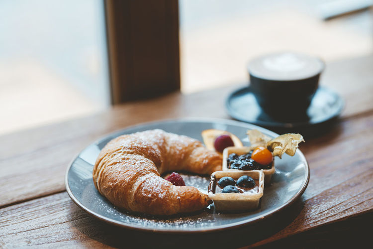 Croissant and coffee on table