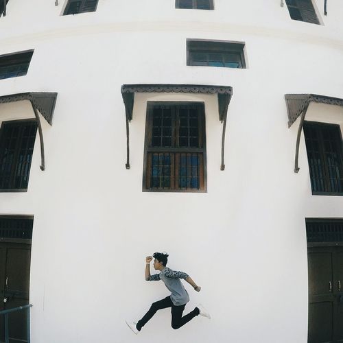 Side view of boy jumping against buildings in city