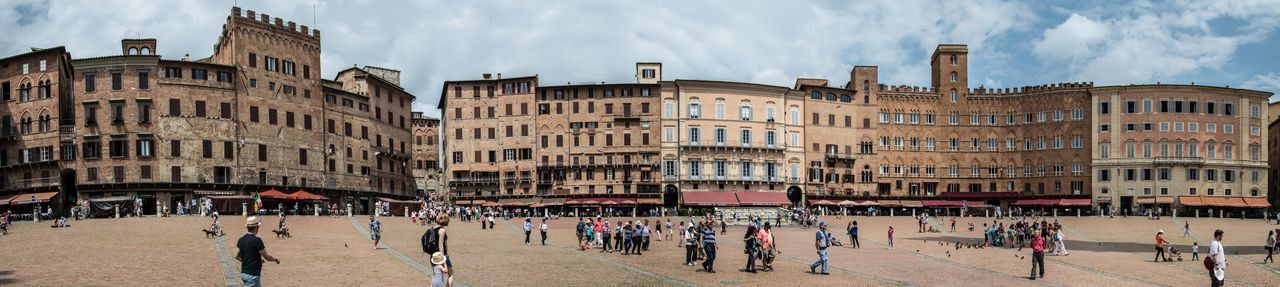Crowd at piazza del campo against cloudy sky