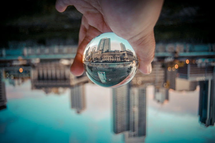Cropped hand of person holding crystal ball with reflection