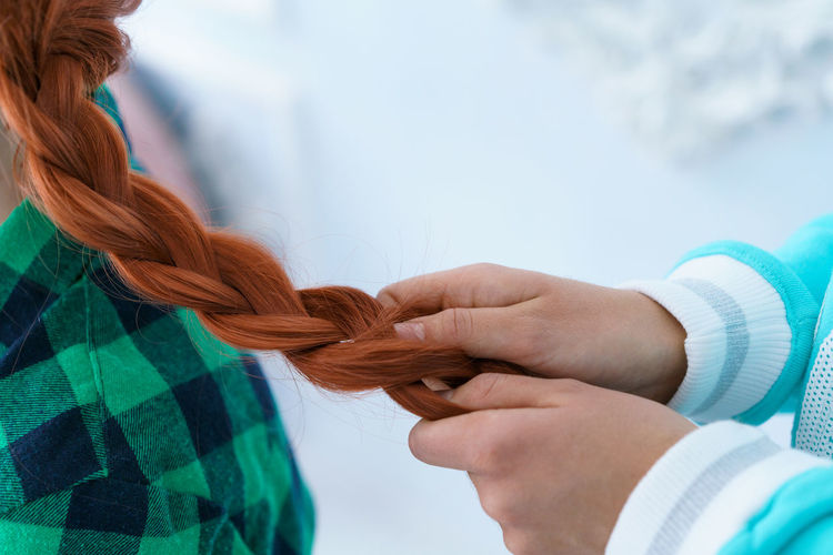A friend is braiding a braid for a red-haired girl.