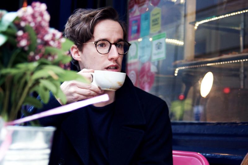 Close-up of handsome young man drinking coffee at cafe