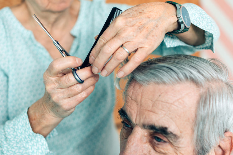 Woman haircuts a senior man - home voluntary assistance - taking care of other - life  third age