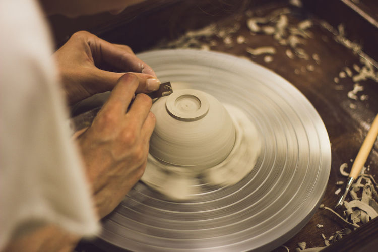 Cropped hands of person working on pottery wheel