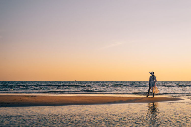 Man on beach against sky during sunset
