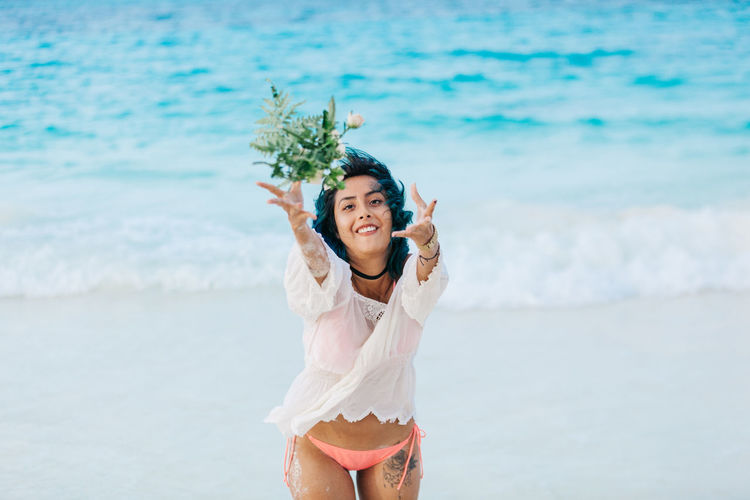 Woman throwing flowers against sea