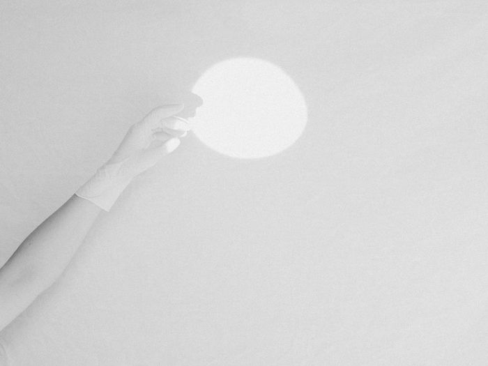 Shadow of hand holding glass against white background