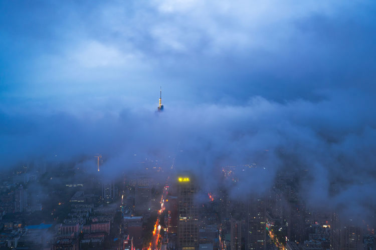 Aerial view of illuminated buildings in city during foggy weather
