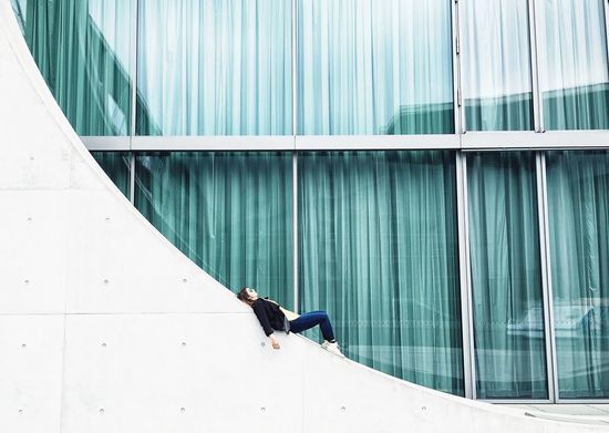 Woman lying on wall against building