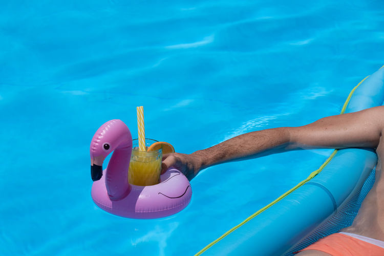 Midsection of person with umbrella on swimming pool