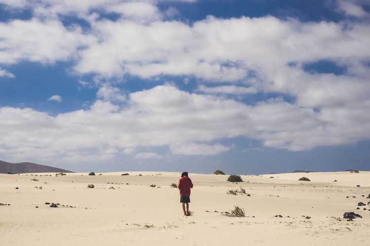 Woman walking on desert against sky