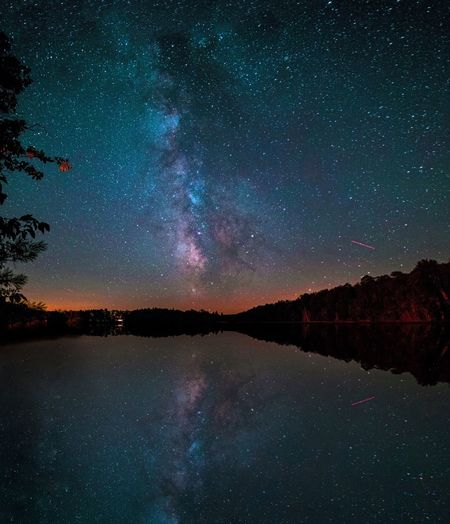 Scenic view of galaxy reflection in lake against sky at night