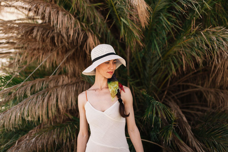 Woman wearing hat while standing against palm trees