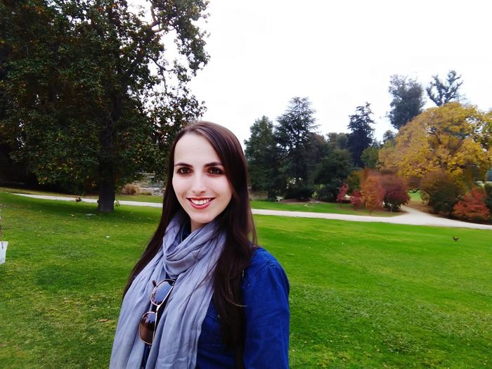 Portrait of smiling young woman standing against trees