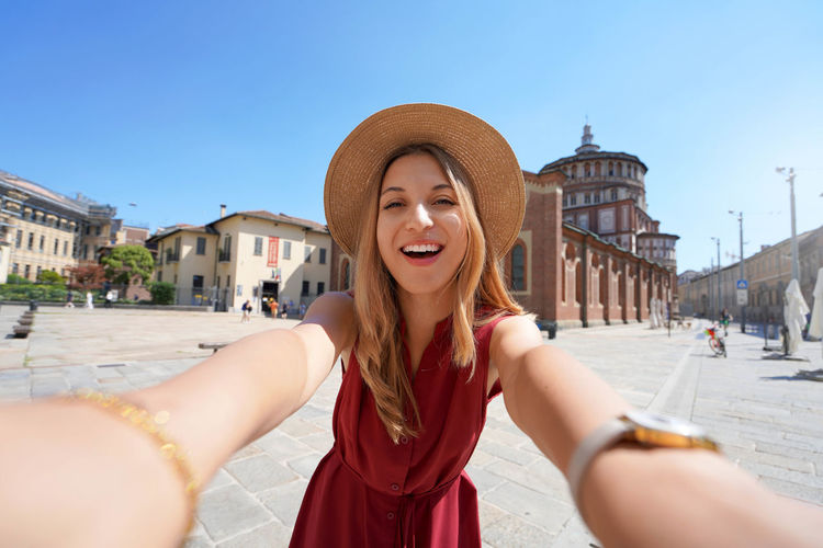 Smiling tourist takes selfie with the church of santa maria delle grazie