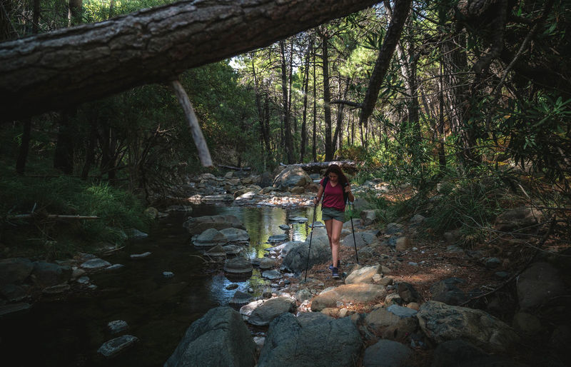 Woman standing by stream in forest