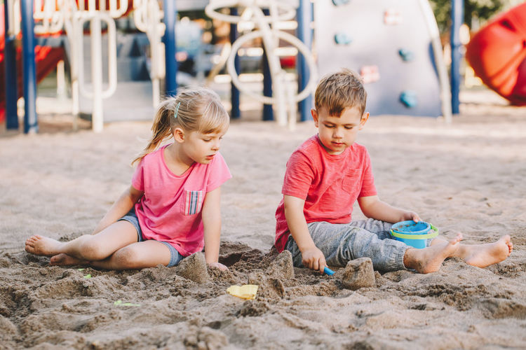 Cute siblings playing while sitting on sand