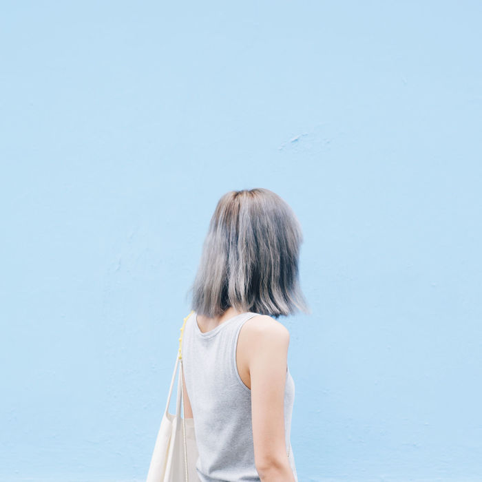 Woman walking standing against blue wall