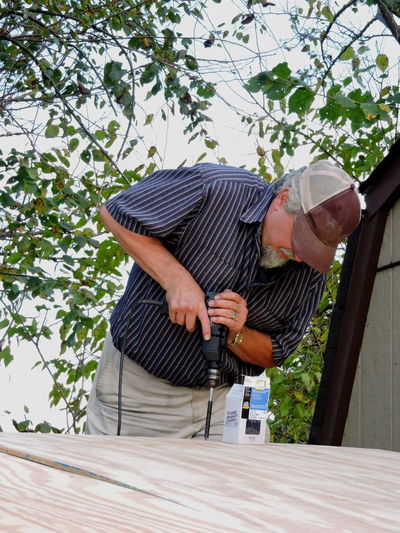Man drilling wood outdoors