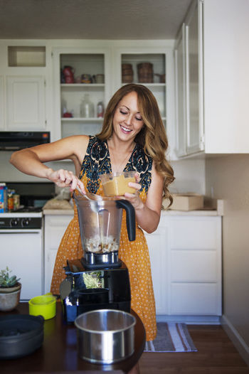 Woman using blender in kitchen