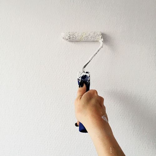 Cropped hand of woman painting wall at home