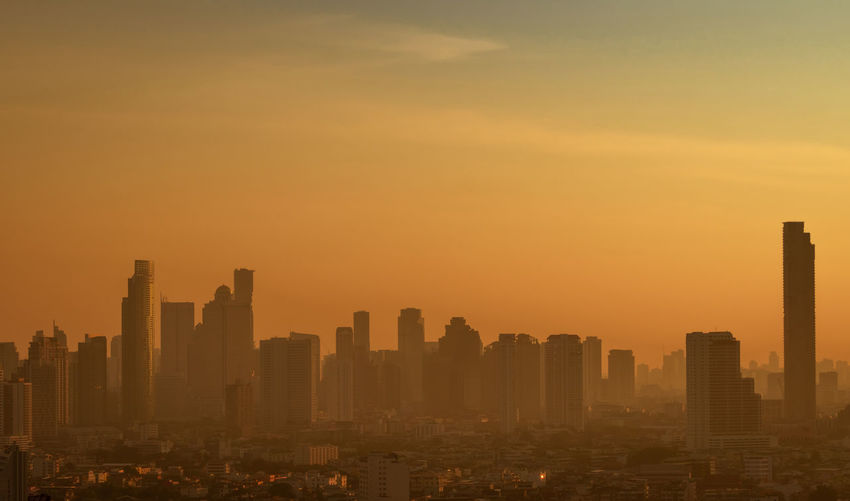 Air pollution. smog and fine dust of pm2.5 covered city in the morning with orange sunrise sky. 
