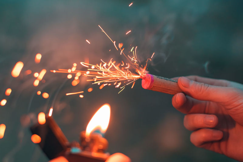 Cropped image of hand holding firecracker against blurred background