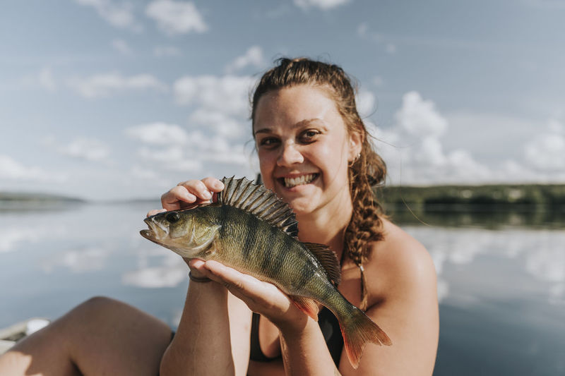 Smiling woman on boat holding fish